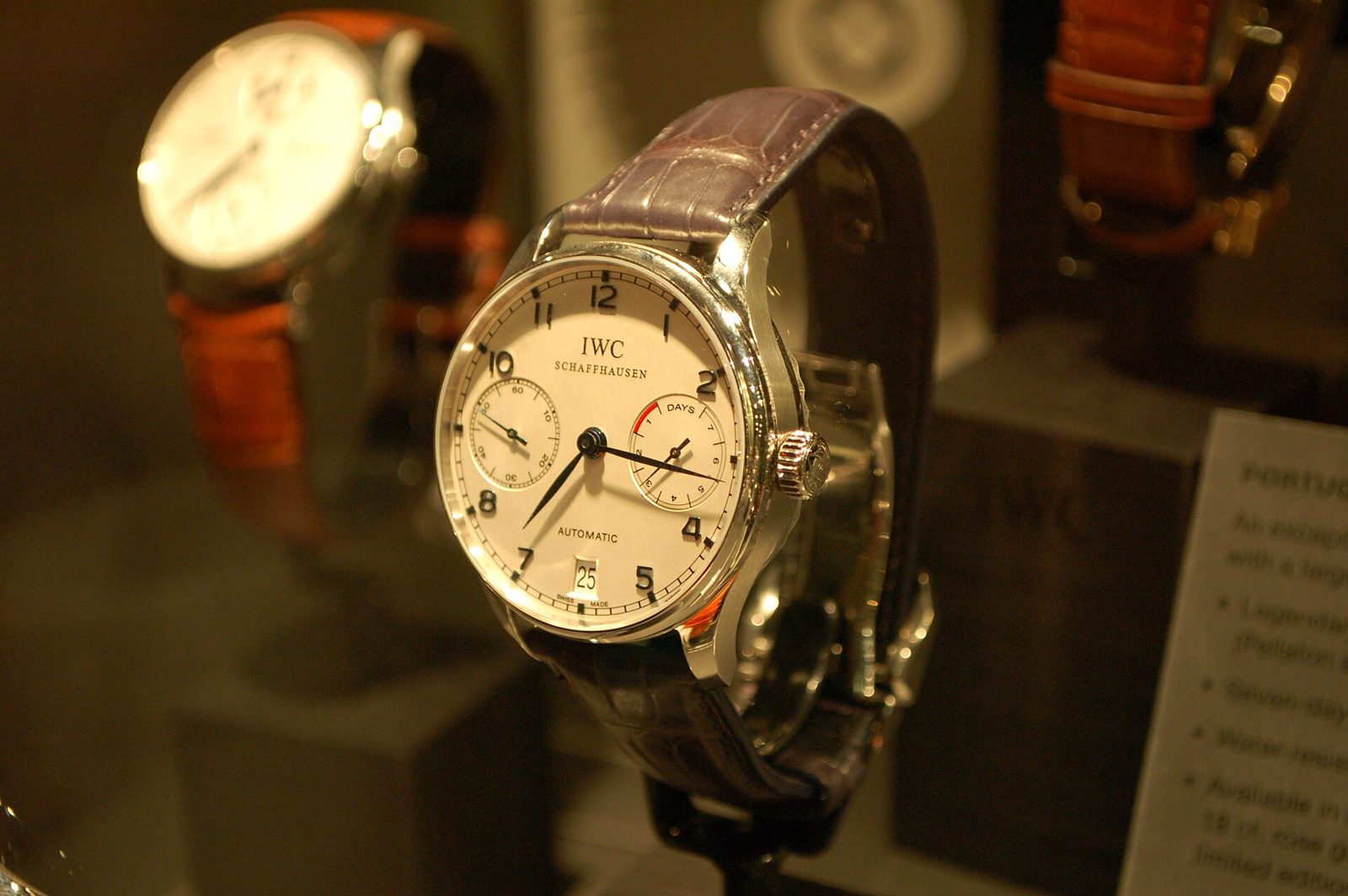 Weisses Zifferblatt einer IWC Portugieser mit kleiner Sekunde, Gangreserveanzeige und Datum an einem Lederband in einer Vitrine