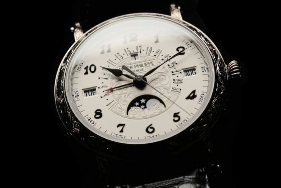 Patek Philippe mit ewigem Kalender, Mondphase, Wochentag- und Monatsfenster und von Hand graviertem Gehäuse vor schwarzem Hintergrund