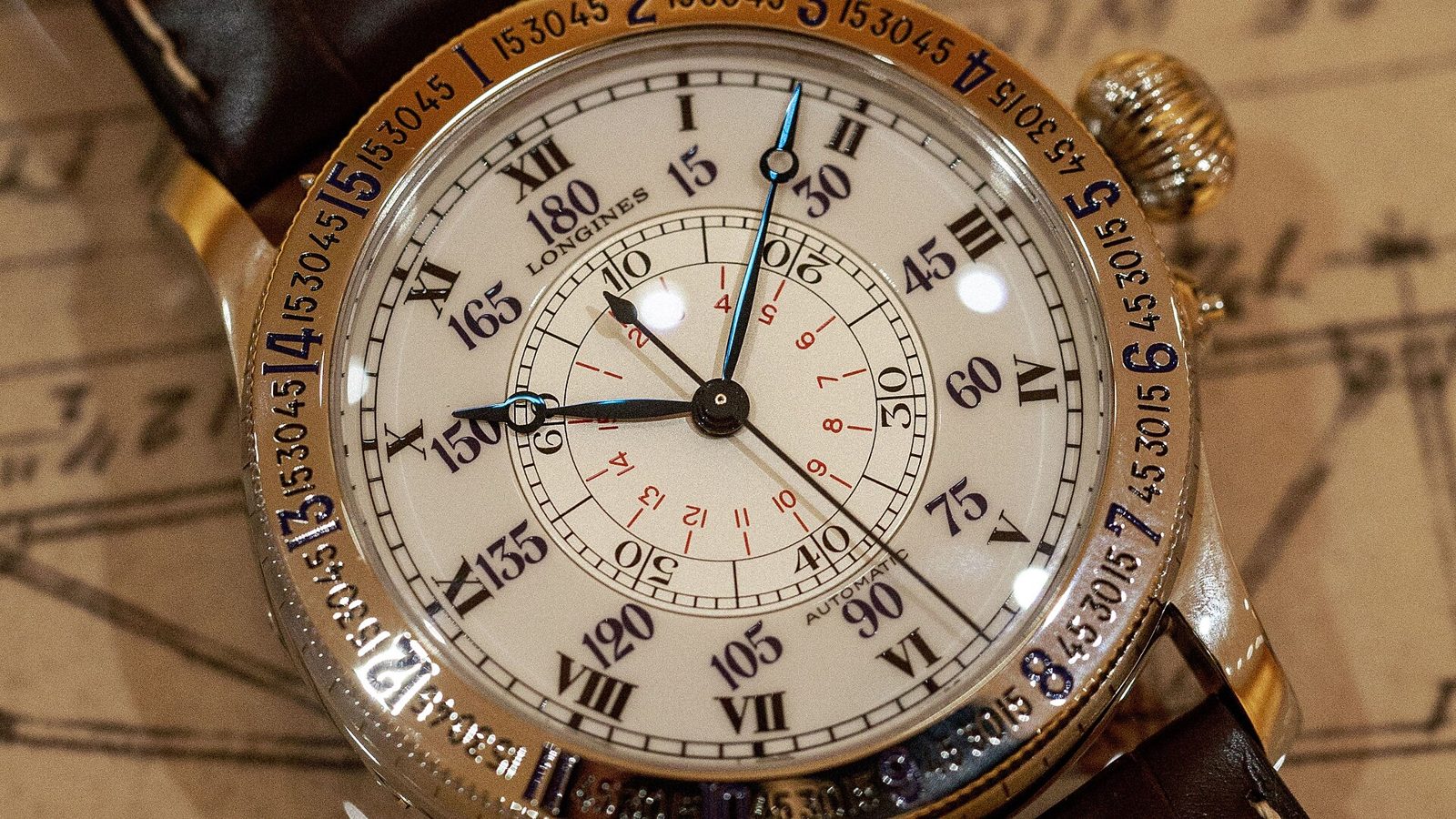 Nahaufnahme einer Longines Hour-Angle-Uhr mit cremefarbenem Zifferblatt, römischen Ziffern, Gradzahlen und drehbarer Lünette mit Minutenskala