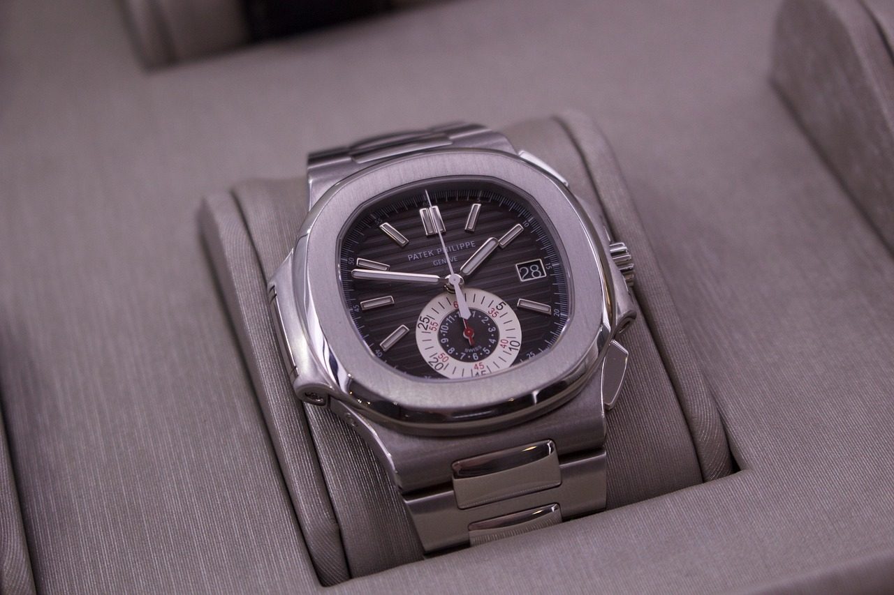 Stählerne Patek Philippe Nautilus mit dunkel gestreiftem Zifferblatt, Datum und weissem Chronographen-Totalisator auf einem grauen Uhrenkissen