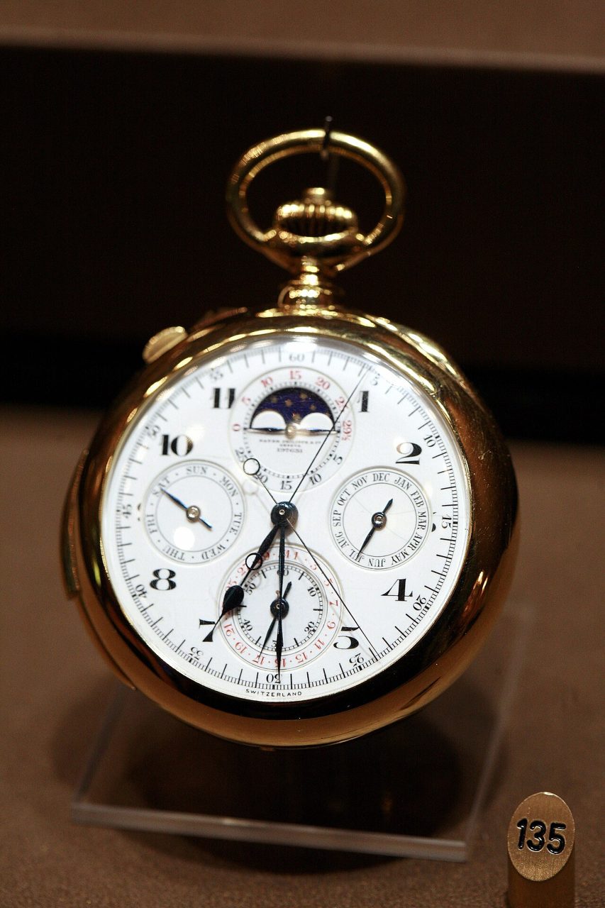 Goldene Taschenuhr von Patek Philippe mit weissem Zifferblatt, Mondphase, ewigem Kalender und Chronographen-Zählern auf einem Plexiglas-Ständer