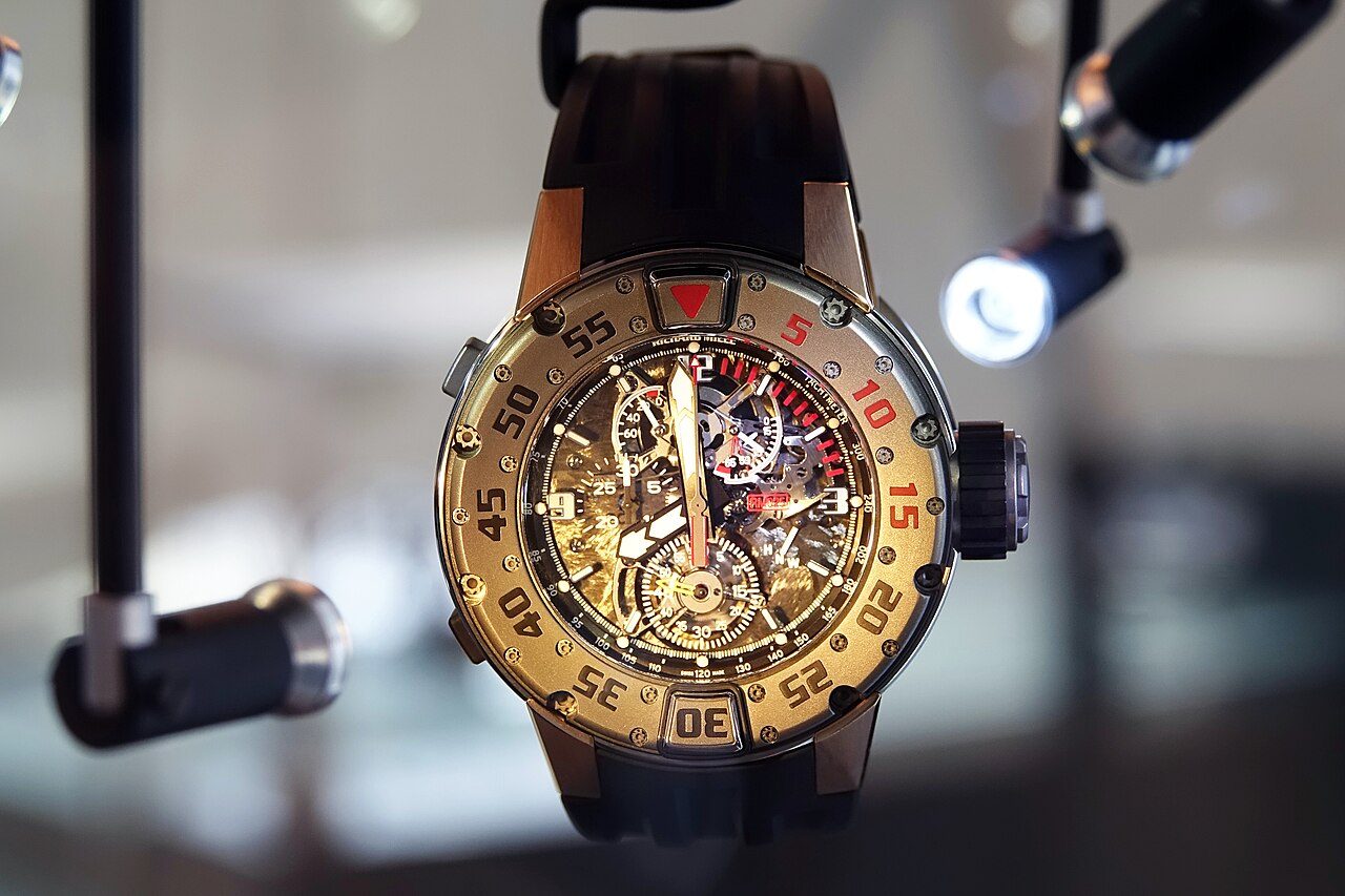 Runde Taucheruhr von Richard Mille mit drehbarer goldfarbener Lünette, Skelett-Zifferblatt mit Chronographen-Anzeigen und schwarzem Kautschukband