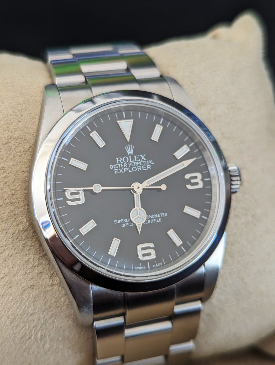 Rolex Explorer mit schwarzem Zifferblatt, den Ziffern 3, 6 und 9 und Oyster-Armband auf einem Uhrenkissen