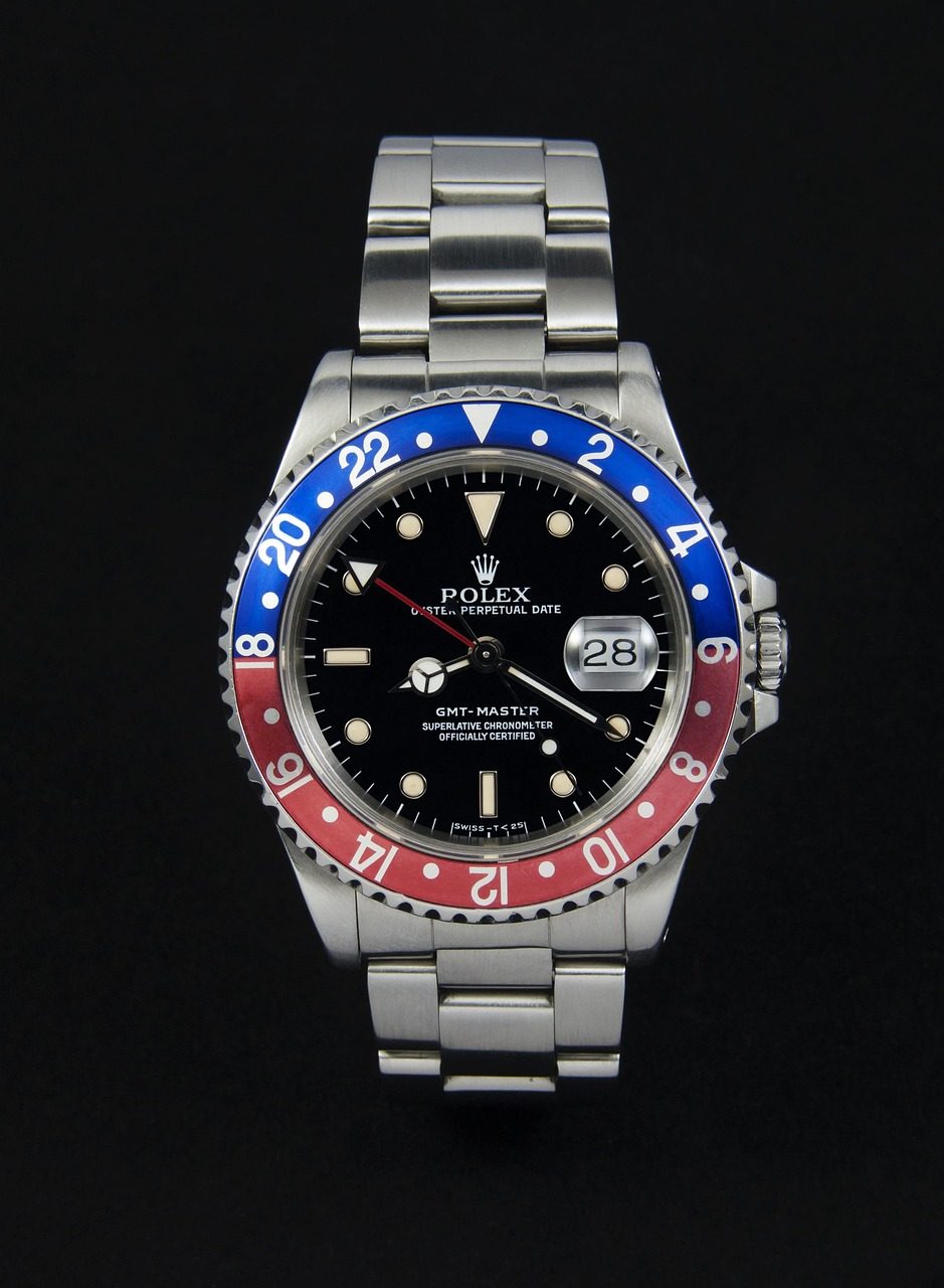 Stählerne Rolex GMT-Master mit rot-blauer Aluminiumlünette, schwarzem Zifferblatt und Oyster-Band vor schwarzem Hintergrund