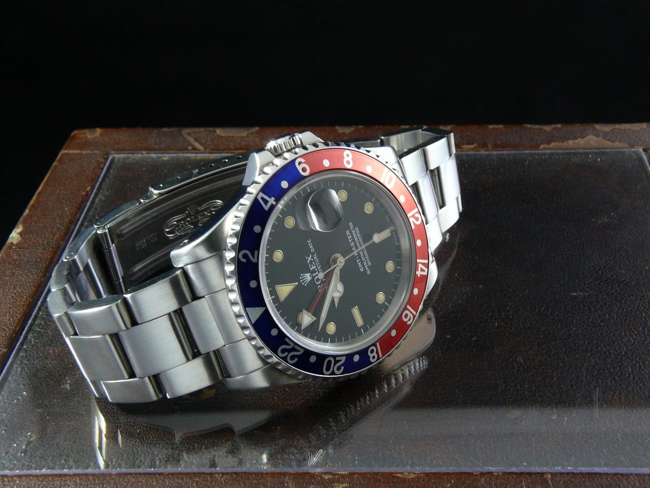 Rolex GMT-Master mit rot-blauer Lünette liegend auf einer Glasplatte, von der Seite fotografiert