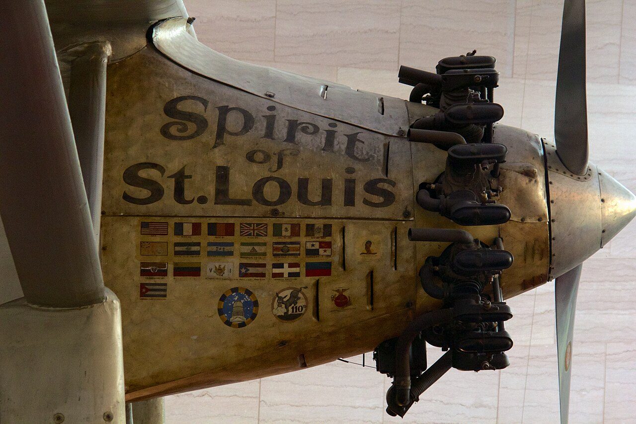 Nahaufnahme des goldgelben Rumpfbugs eines Flugzeugs mit dem Schriftzug «Spirit of St. Louis», kleinen Länderflaggen darunter und einem Motor mit freiliegenden Zylindern